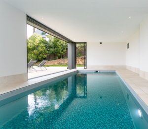 création de piscine intérieure, immense baie vitrée qui s'ouvre vers l'extérieur