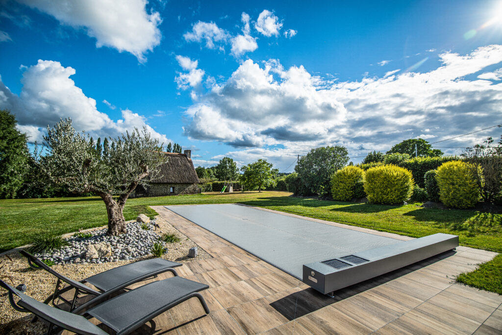 Vue d’ensemble d’une piscine protégée par une couverture Coverseal gris foncé dans un jardin contemporain en Bretagne