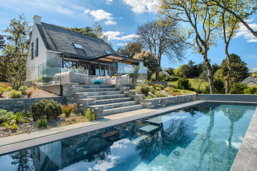 Maison bretonne surplombant une piscine avec double escalier suspendu, en bord de mer